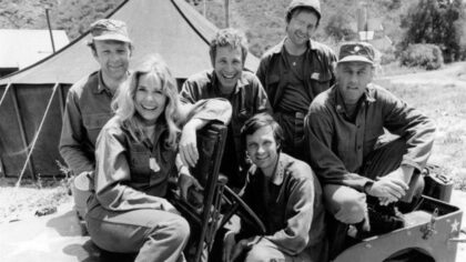 Ze seriálu M*A*S*H (1974), Alan Alda na místě řidiče. Zdroj: CBS Television – Na Commons přenesl z en.wikipedia uživatel We hope pomocí nástroje CommonsHelper.(Original text : eBay itemphoto frontphoto back), Volné dílo, https://commons.wikimedia.org/w/index.php?curid=16354650